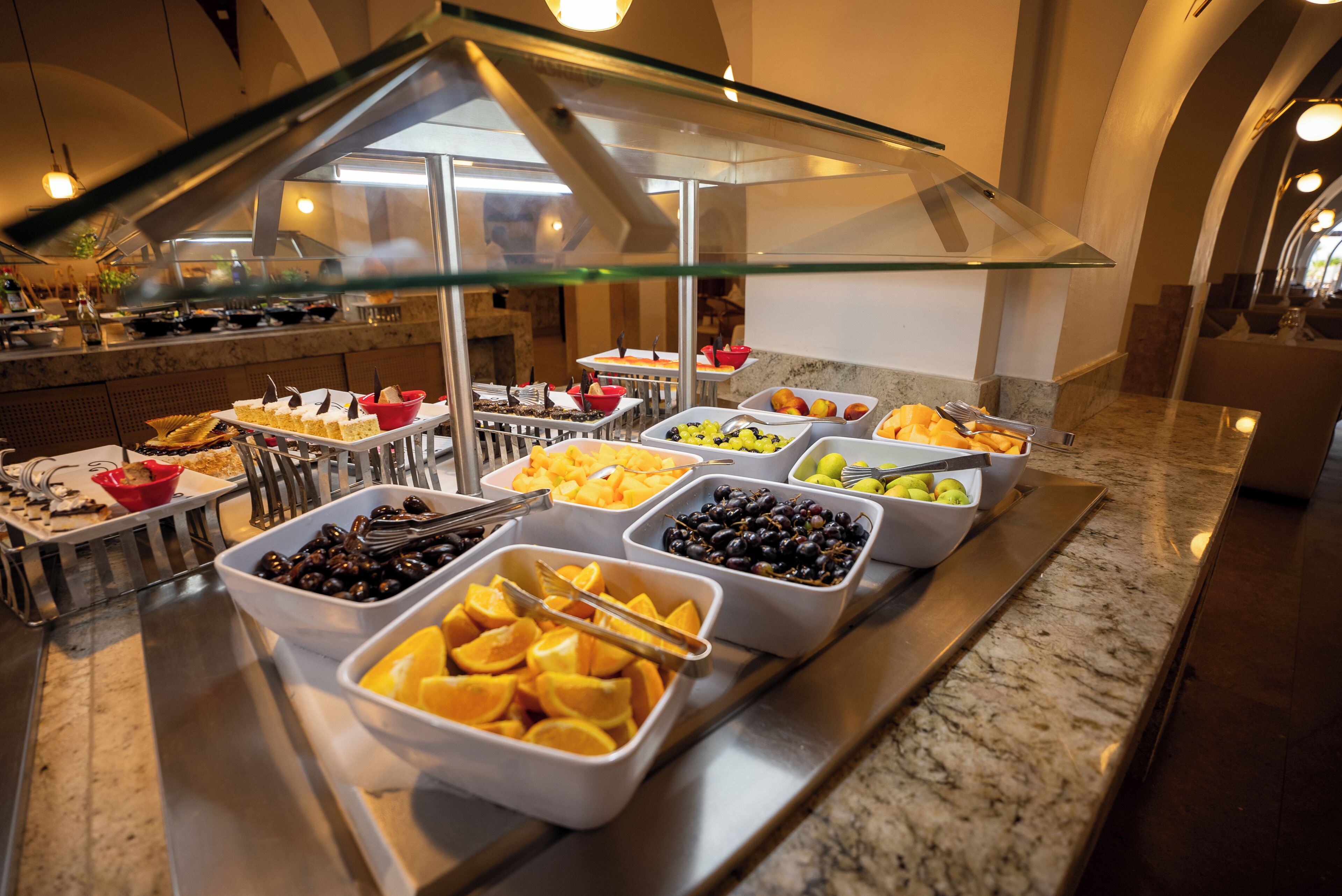 Un buffet con diverse pietanze, tra cui frutta, verdura e dolci.