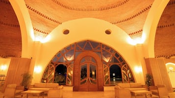 Eine Lobby mit hohem Rundbogenportal, Sitzgelegenheiten und einer Ziegeldecke.