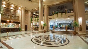 A spacious lobby with a central circular floor design, large columns, and a balcony with plants. - Shams Safaga Resort - All inclusive (Safaga)