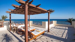 A wooden pergola with lounge chairs and a view of the ocean. - Imperial Shams Abu Soma - All inclusive (Safaga)