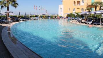 Una piscina techada, una piscina al aire libre, sombrillas