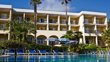 Una piscina techada, una piscina al aire libre, sombrillas