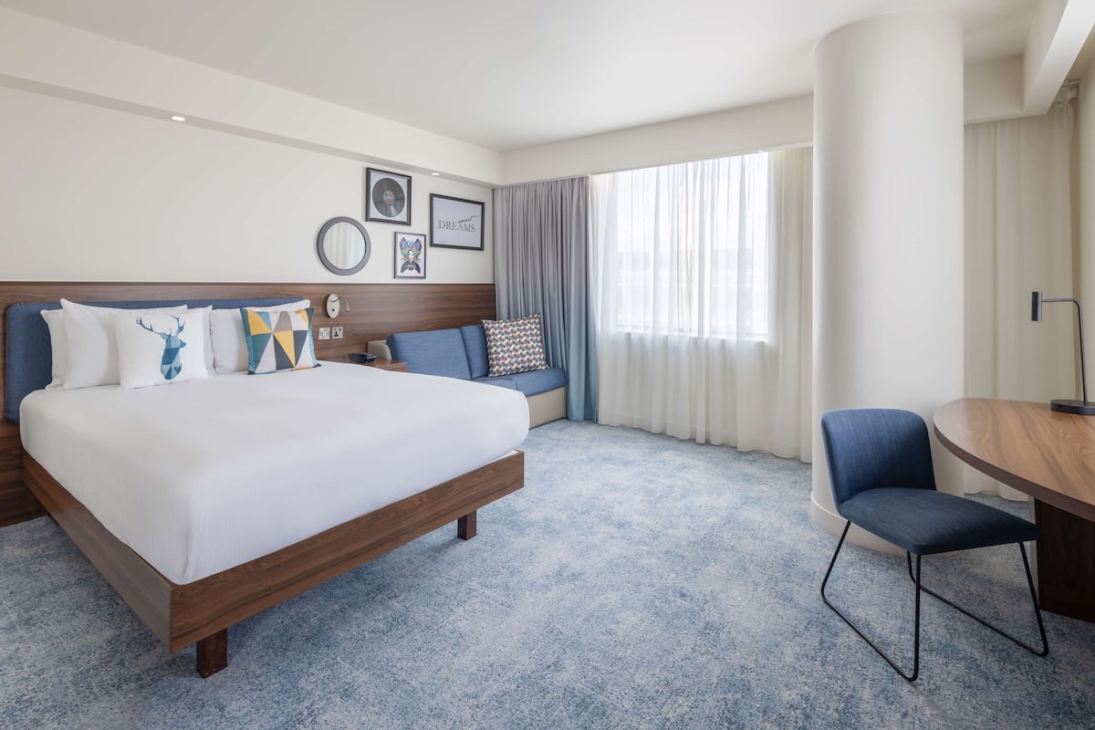 Une chambre d’hôtel dotée d’un grand lit, d’un coin salon, d’une table à manger et offrant une vue sur l’extérieur.