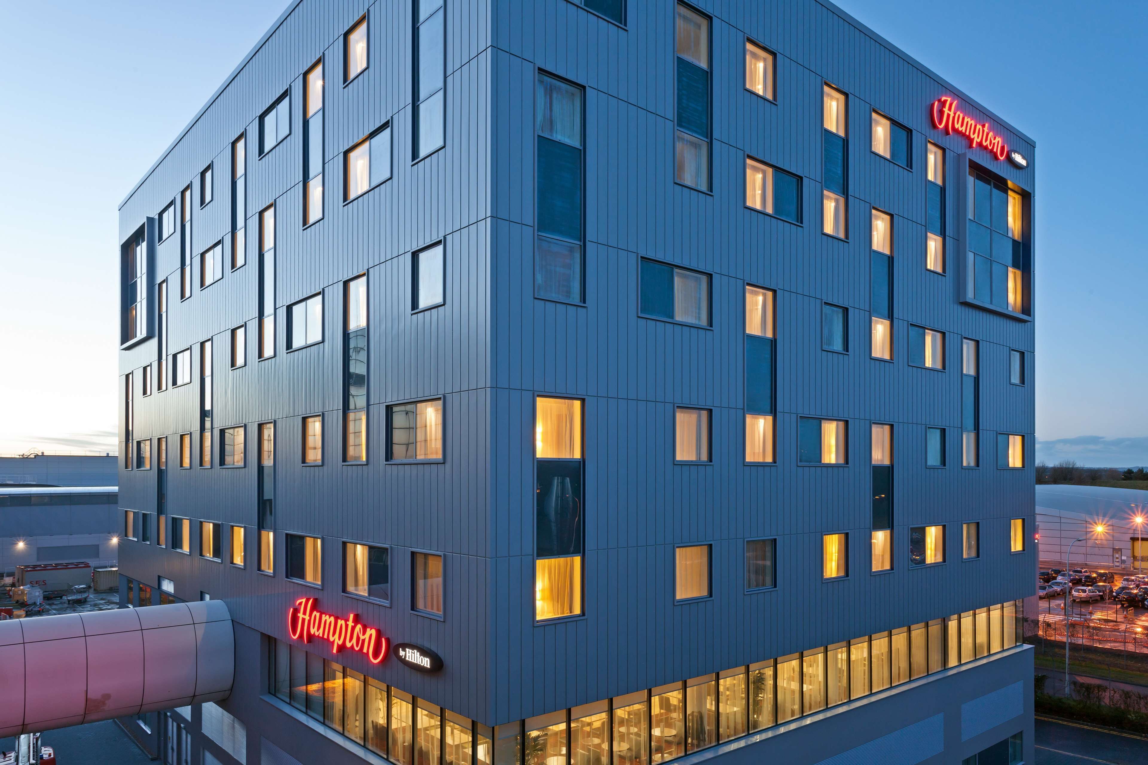 A modern hotel building with a blue facade and multiple windows.