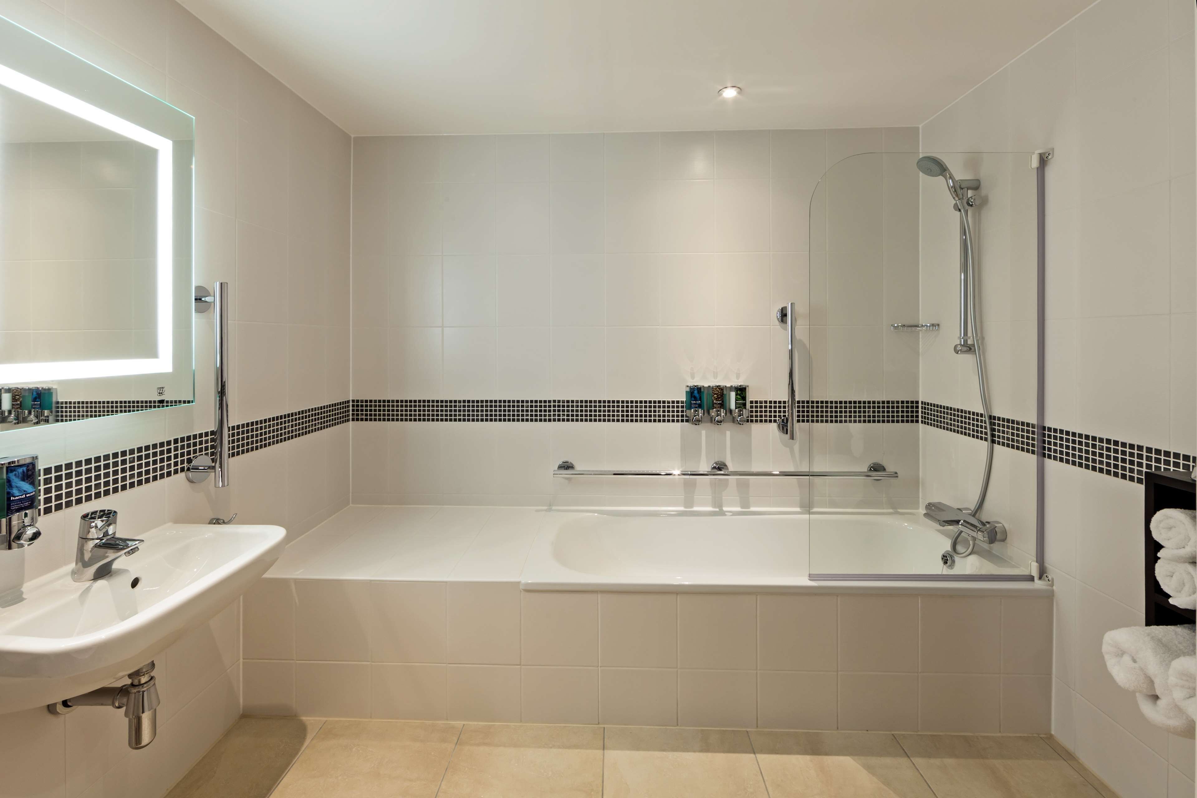 Une salle de bain moderne dotée d’une grande baignoire, d’une douche séparée et d’un meuble-lavabo avec un miroir.