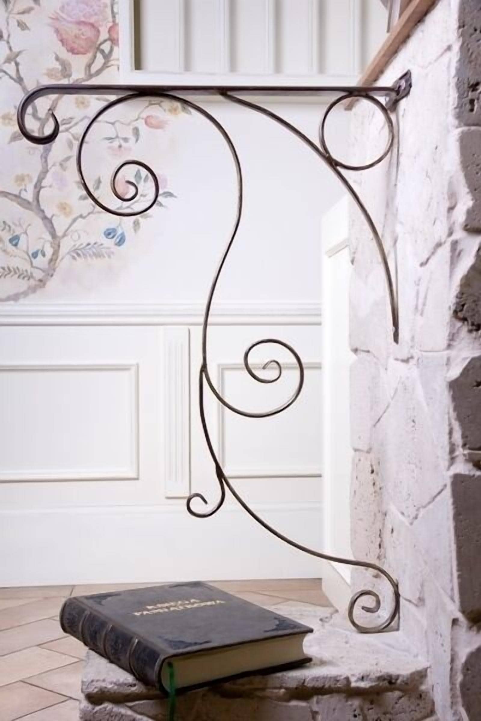 Une lettre décorative en métal, en forme de « D », fixée à un mur, avec un livre placé en dessous.