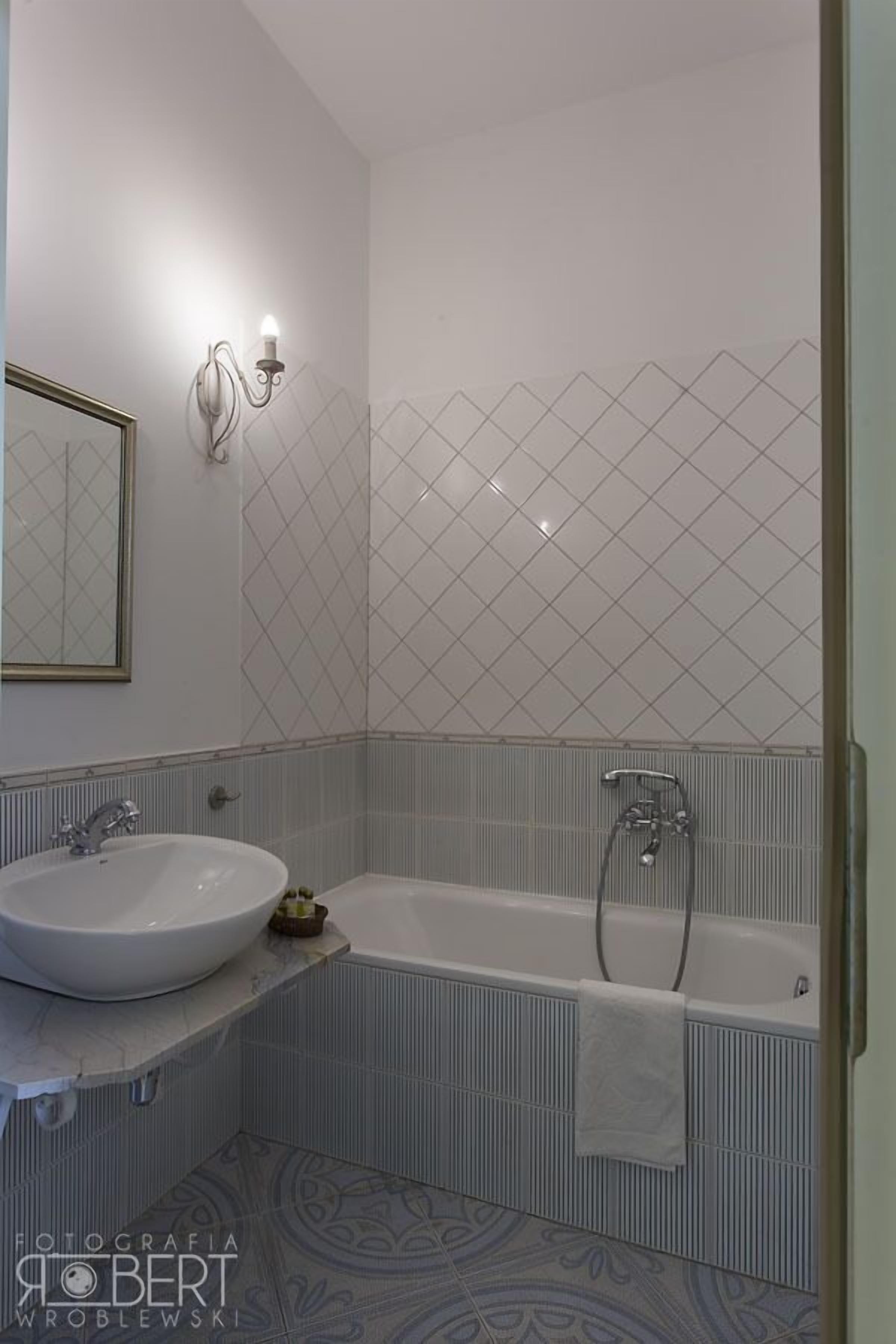 A bathroom with a white sink, a bathtub, and a shower. There is a towel hanging on the wall.