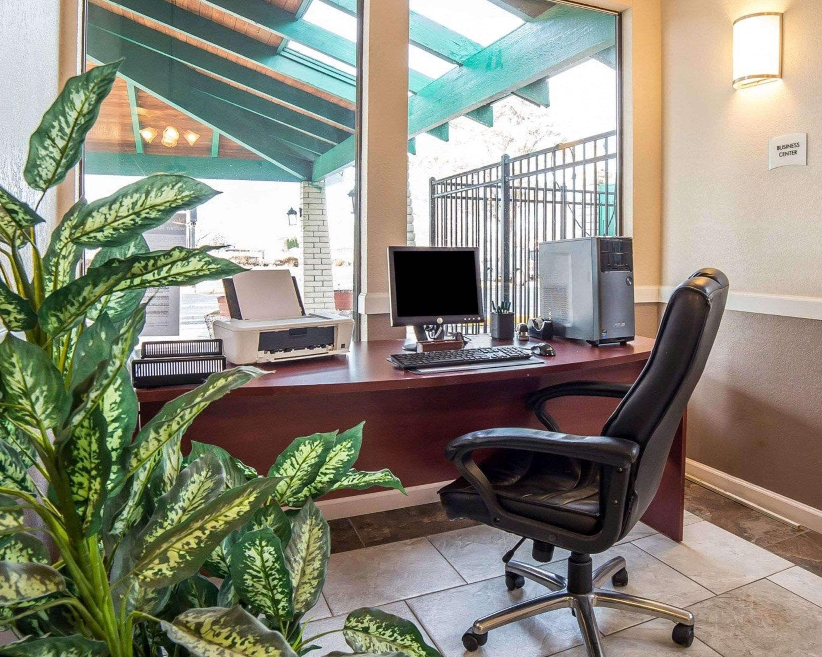 A reception desk with a computer, printer, and a chair.