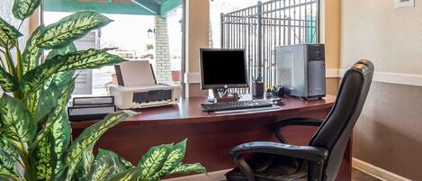 A reception desk with a computer, printer, and a chair.