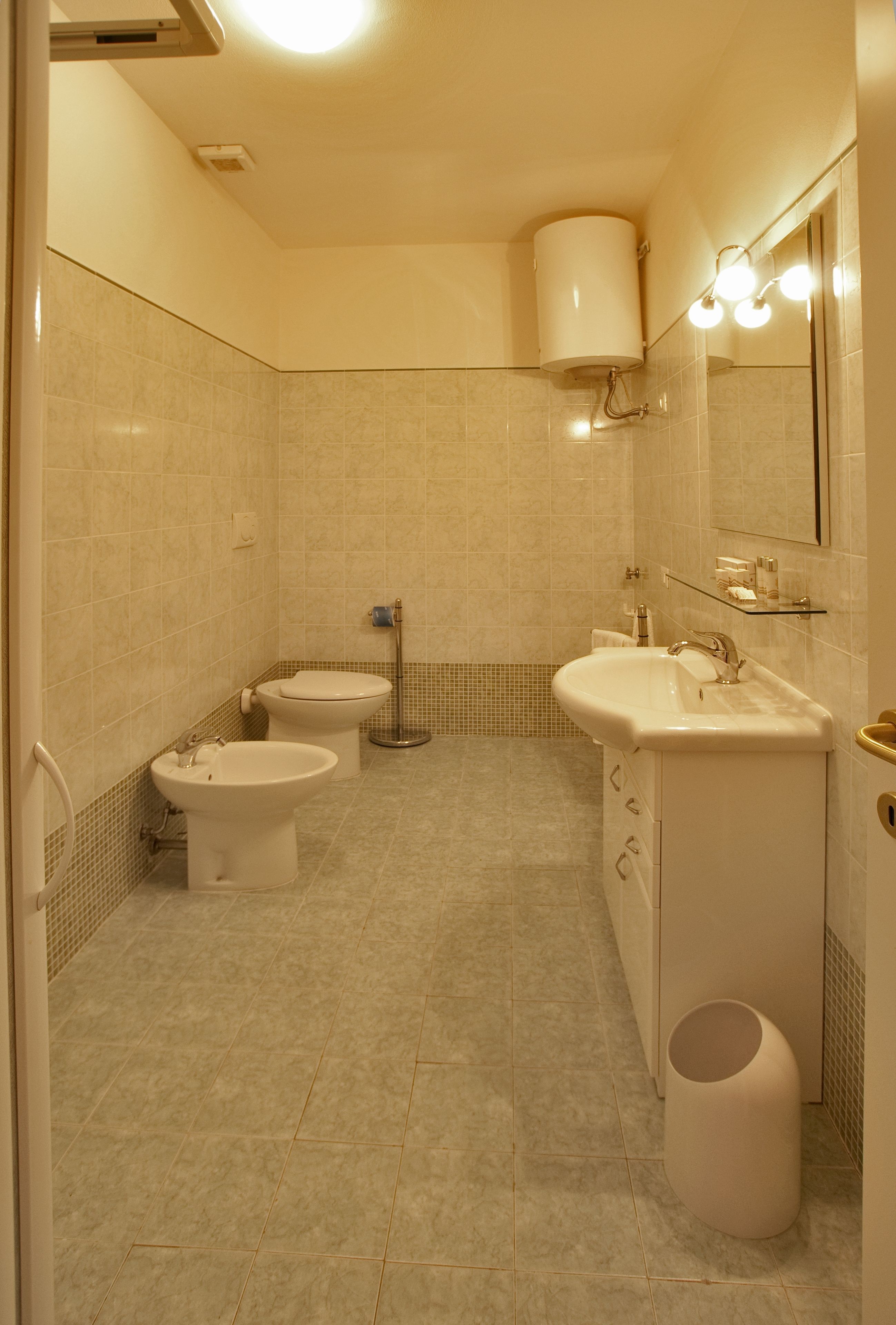 A bathroom with two toilets, a sink, and a mirror.