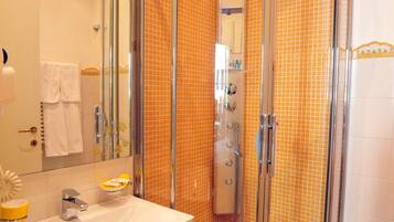 A shower enclosure with a glass door, a sink with a mirror, and a tiled floor.