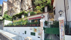 Un edificio con fachada blanca, portón verde y un mural en la pared.