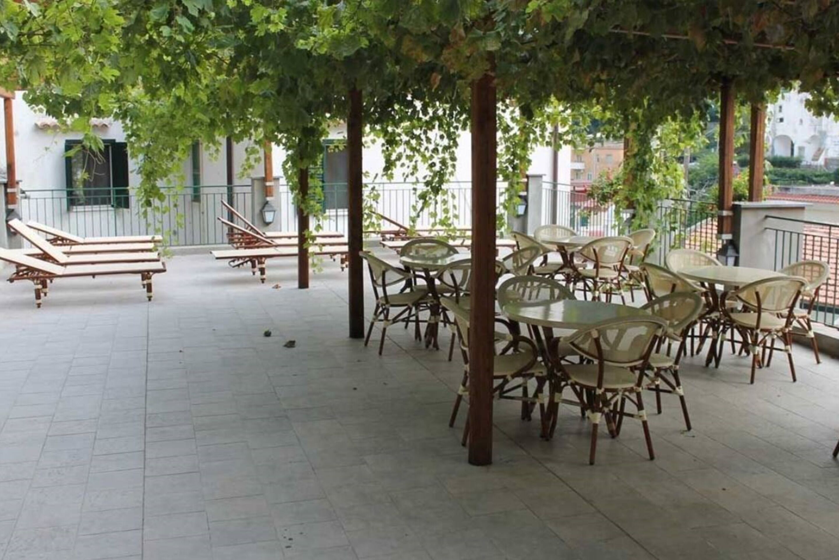 Un espace extérieur aménagé en terrasse, avec des tables et des chaises, entouré d’arbres et doté d’une rambarde.