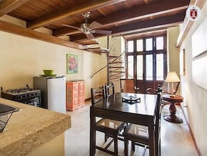 Une cuisine équipée d’une cuisinière à gaz, d’un réfrigérateur et d’un coin repas avec une table et des chaises.