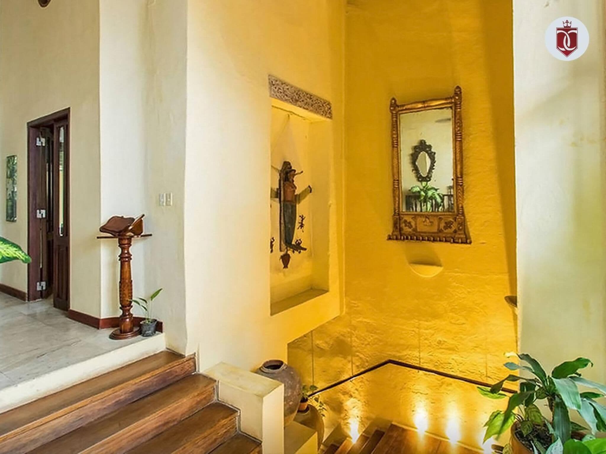 Una scala con gradini in legno che porta a un pianerottolo, uno specchio fissato alla parete e un elemento decorativo a parete.