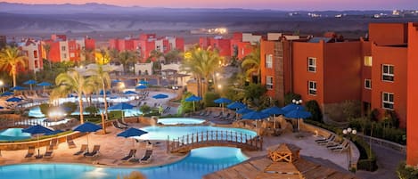 Um resort com piscina, espreguiçadeiras e palmeiras.