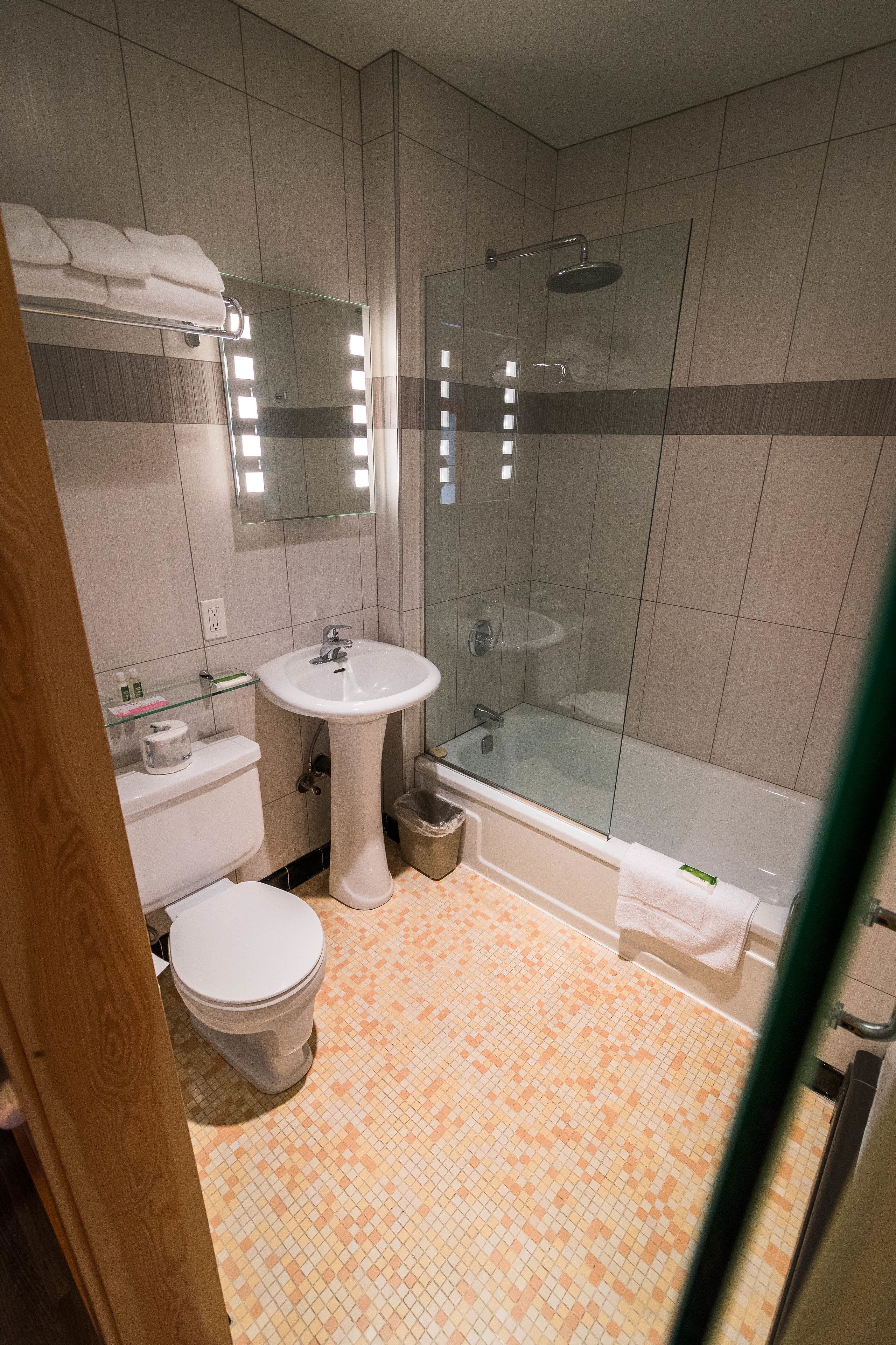Et moderne badeværelse med bruseniche, hvid vask og toilet.
