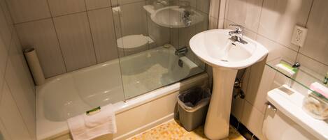 A modern bathroom with a glass-enclosed shower, a pedestal sink, and a toilet.
