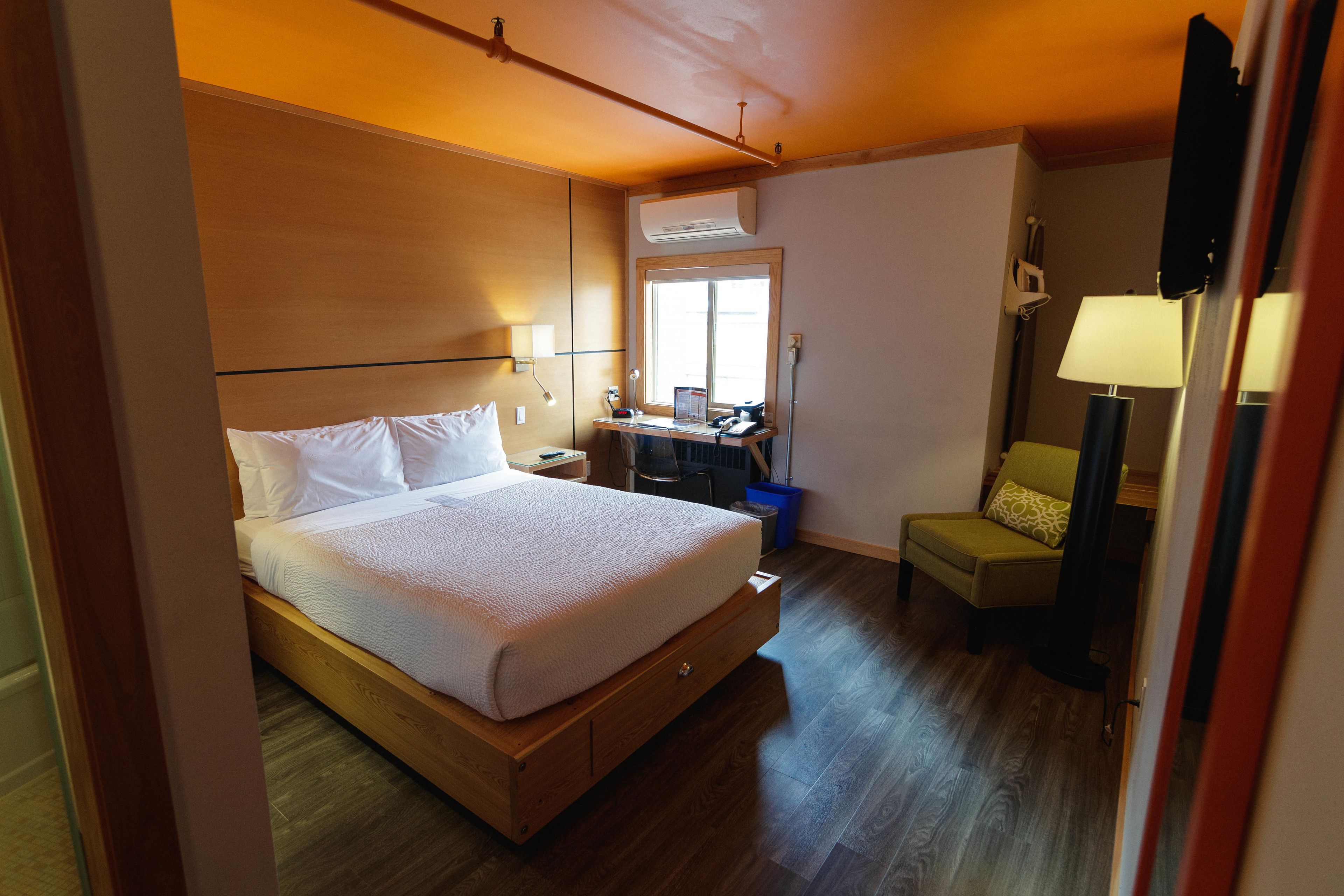 A hotel room with a wooden bed, a desk, a chair, and a window.