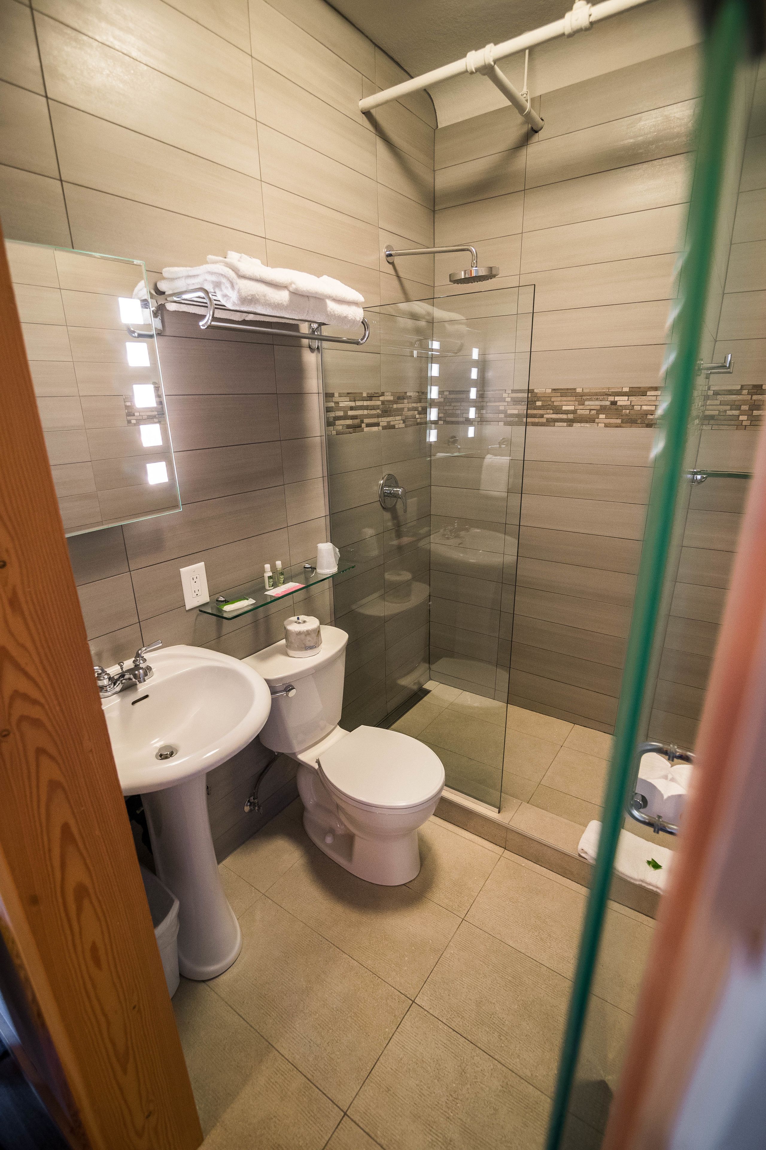 Ein modernes Badezimmer mit einer gläsernen Duschkabine, einem Waschbecken auf Säule und einer Toilette.