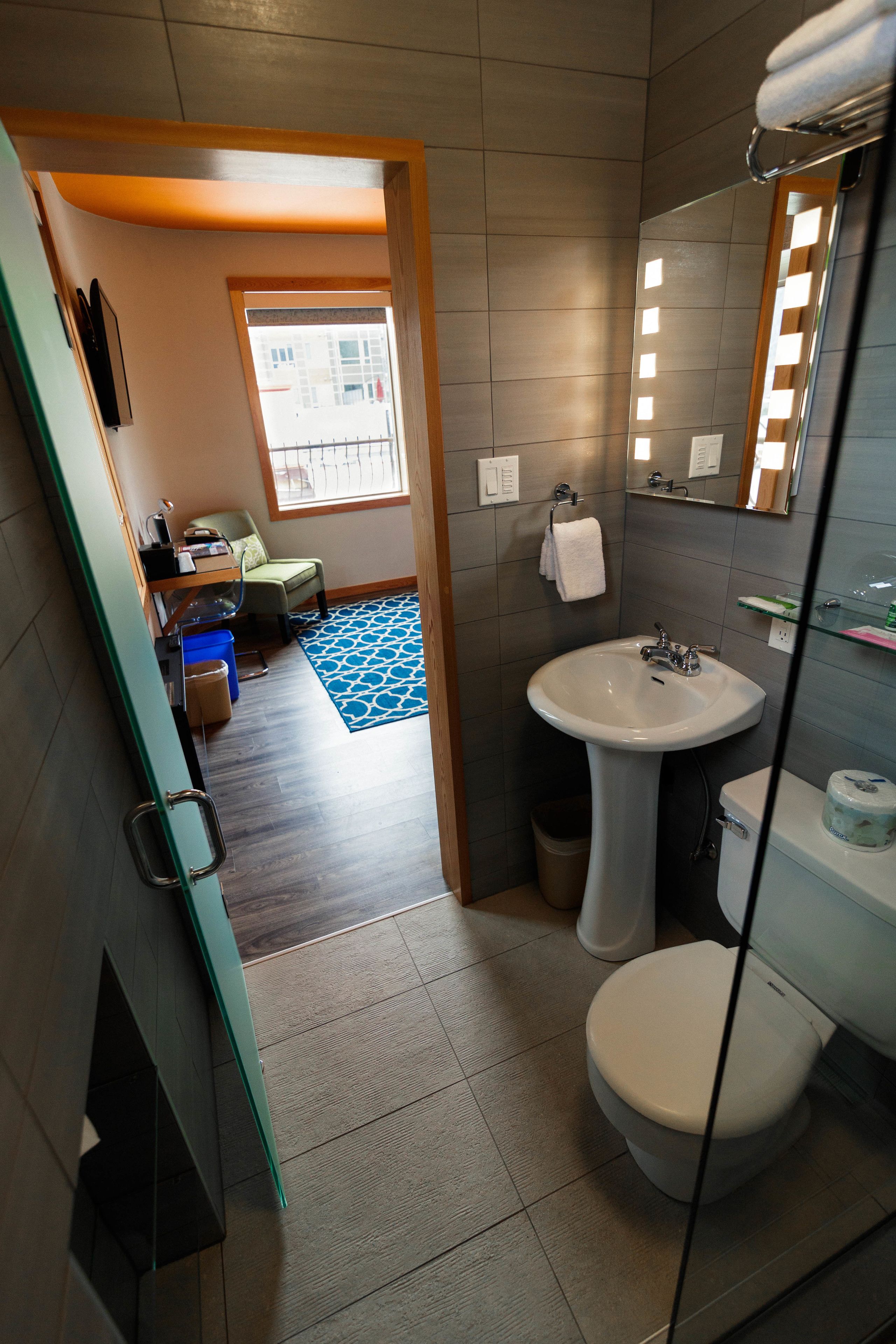 Une salle de bain moderne avec un lavabo sur colonne, des toilettes et un espace douche.