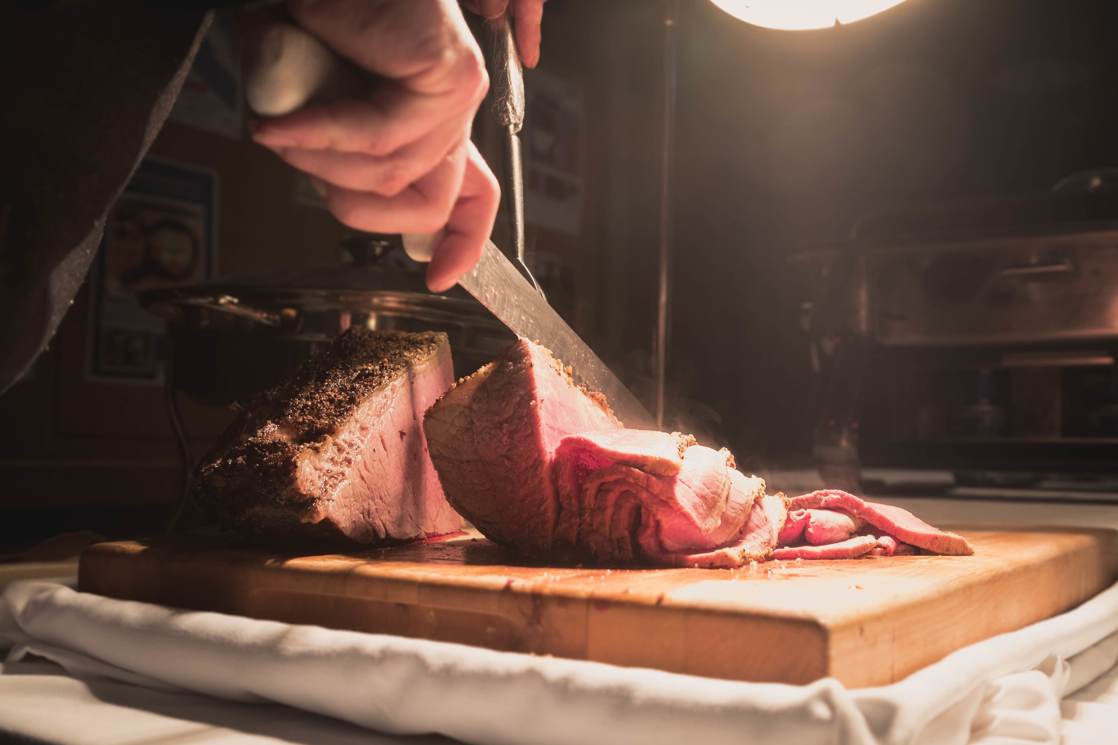 Una persona cortando carne sobre una tabla de madera.