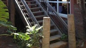 Una escalera conduce a un edificio con techo de paja, rodeado de vegetación tropical.