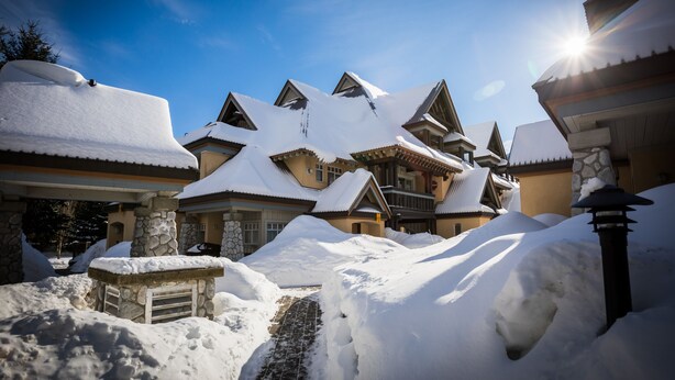 A snow-covered building with a traditional architectural style, featuring multiple roofs and stone pillars. - Stoney Creek Lagoon - Whistler Premier (Whistler)