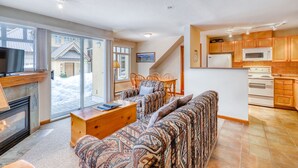 A living room with a fireplace, a sofa, a coffee table, and a television. - Stoney Creek Lagoon - Whistler Premier (Whistler)