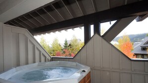 A hot tub in a covered outdoor area with a view of autumn foliage and a house in the background. - Stoney Creek Lagoon - Whistler Premier (Whistler)