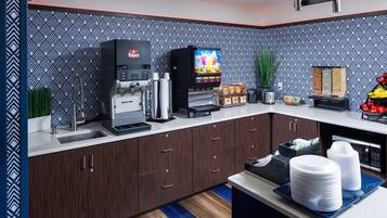 A modern kitchen with a coffee machine, a microwave, and a TV displaying a cooking show.