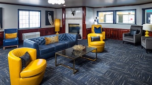 Un salón amplio con un sofá azul, sillones amarillos, una mesa de centro de cristal y una chimenea.