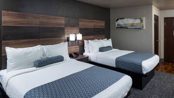 A hotel room with two beds, a modern headboard, a nightstand with a lamp, and a painting on the wall.