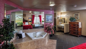 Habitación de hotel con una bañera grande, un tocador de madera, un lavamanos y un espejo.
