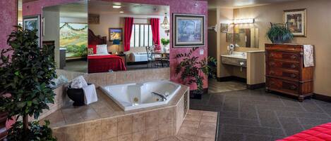 A hotel room with a large bathtub, a wooden dresser, a sink, and a mirror.
