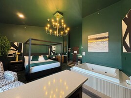 Una habitación de hotel moderna con una cama con dosel, una bañera grande y un área de comedor.