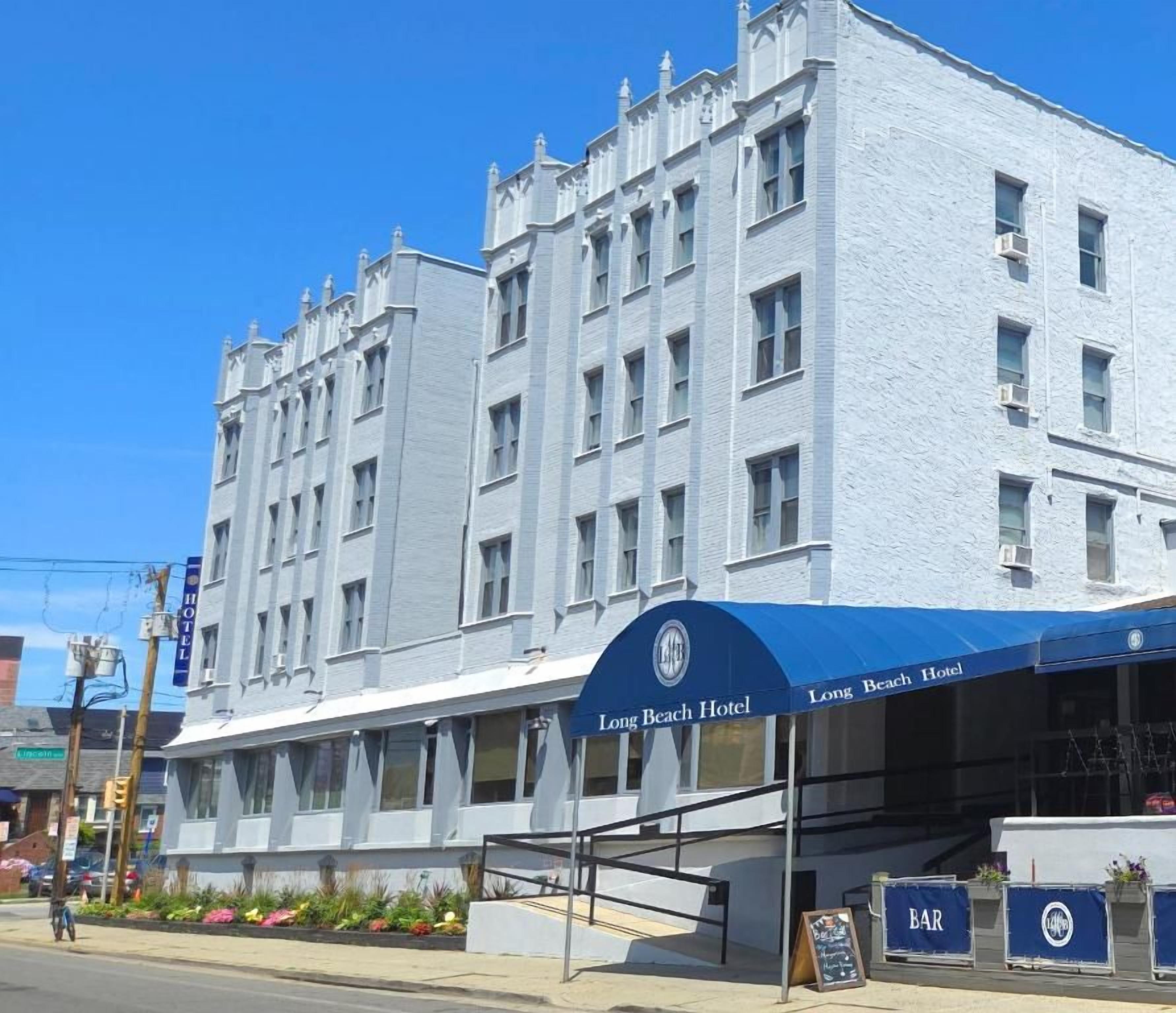 Ein zweistöckiges Hotel mit einer blauen Markise und einem Schild mit der Aufschrift 'Long Beach Hotel'.