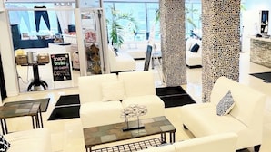 A modern hotel lobby with a reception desk, seating area, and a view of the outside.