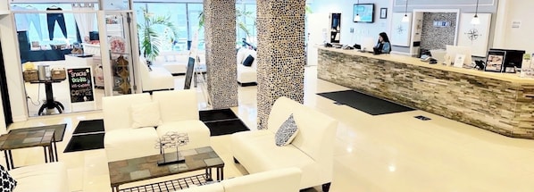 Un moderno vestíbulo de hotel con recepción, zona de estar y vistas al exterior.