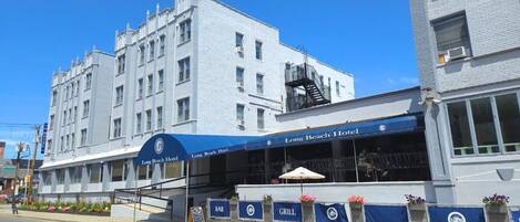 A hotel with a blue awning, outdoor seating area, and a bar.