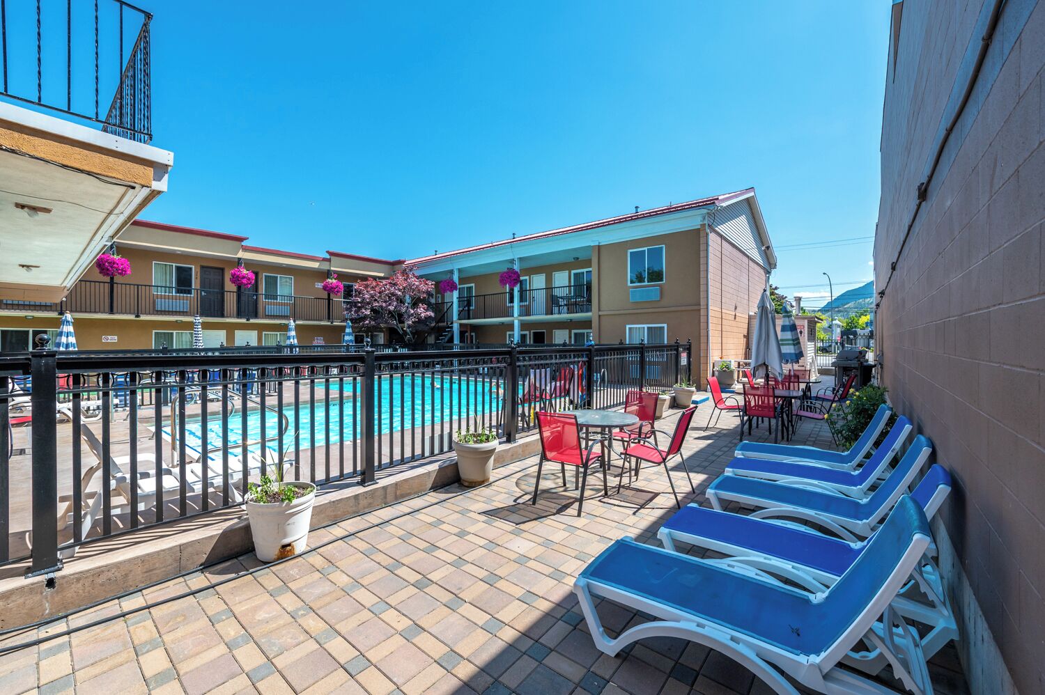 A rooftop pool area with lounge chairs, a pool, and a view of the surrounding buildings.