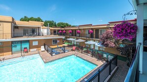 Un hotel con piscina, mobiliario exterior y balcones con jardineras.