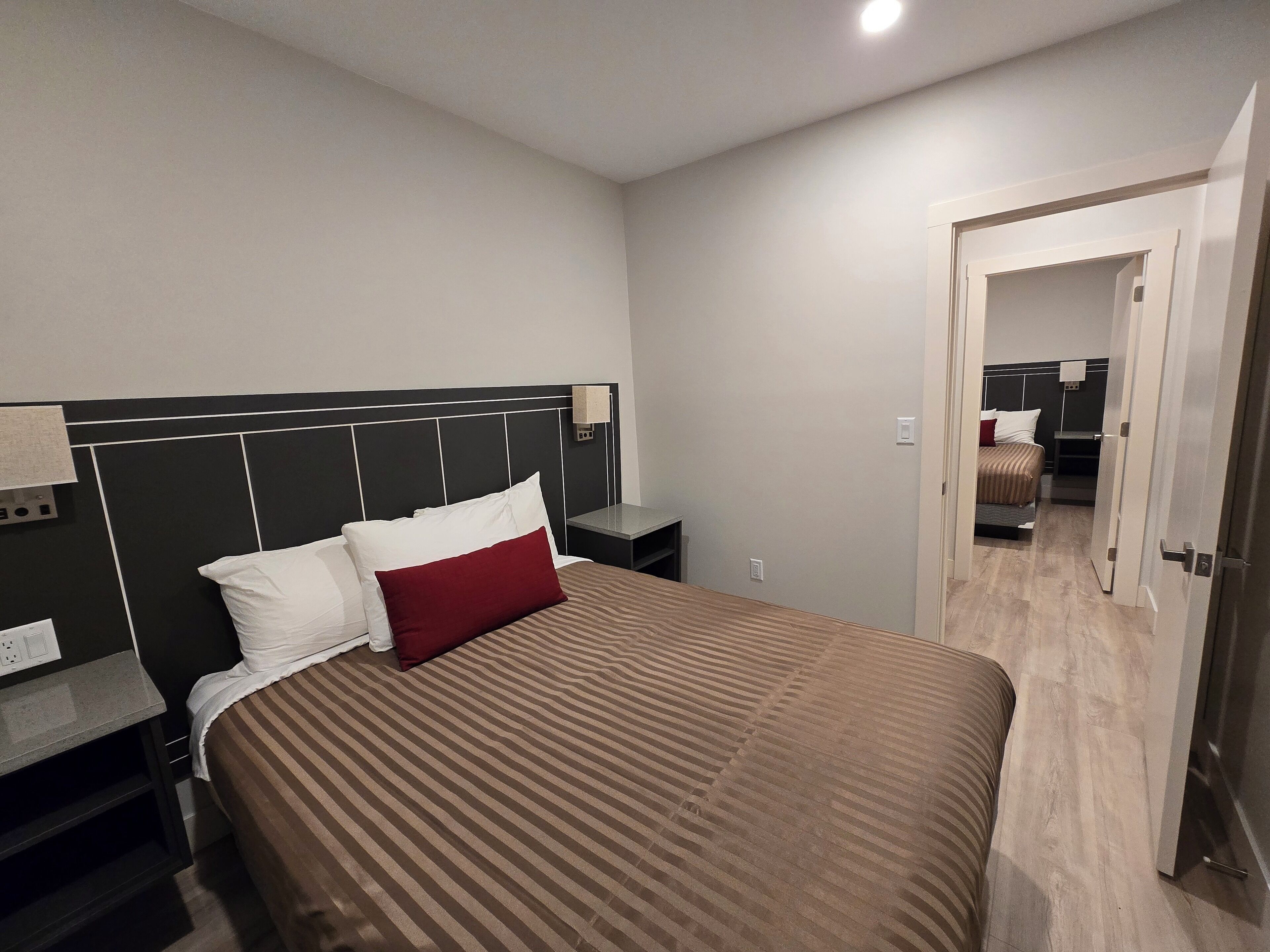 Una habitación de hotel moderna con una cama grande, una mesita de noche y un espejo.