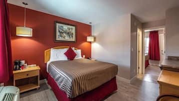 A hotel room with a bed, nightstands, a painting, and a view of a bathroom.