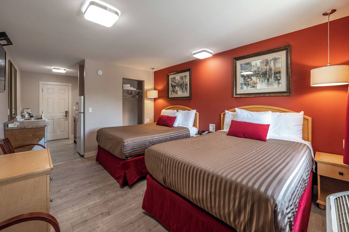Habitación de hotel con dos camas, kitchenette y baño.