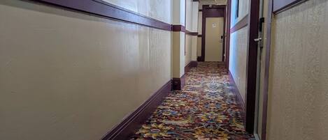 A hallway with patterned carpet and wooden trim.