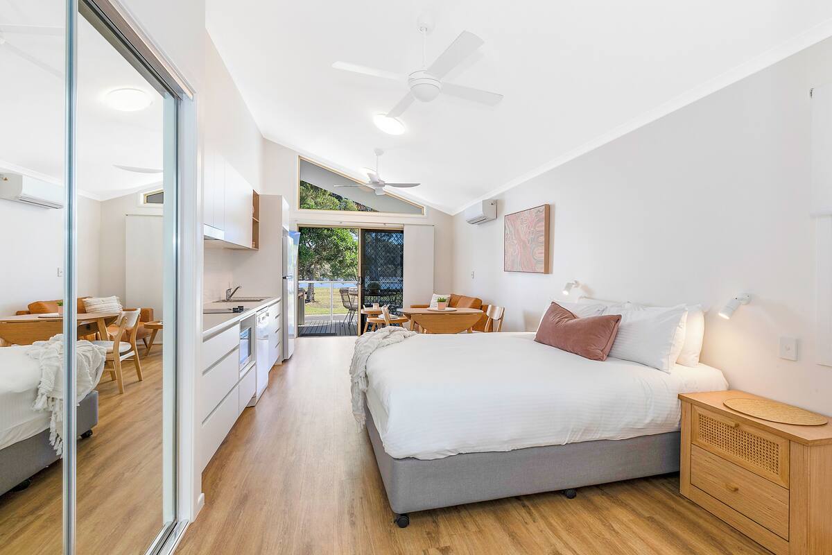 A modern bedroom with a large bed, a desk, and a dining area.