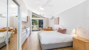 A modern bedroom with a large bed, a desk, and a dining area.