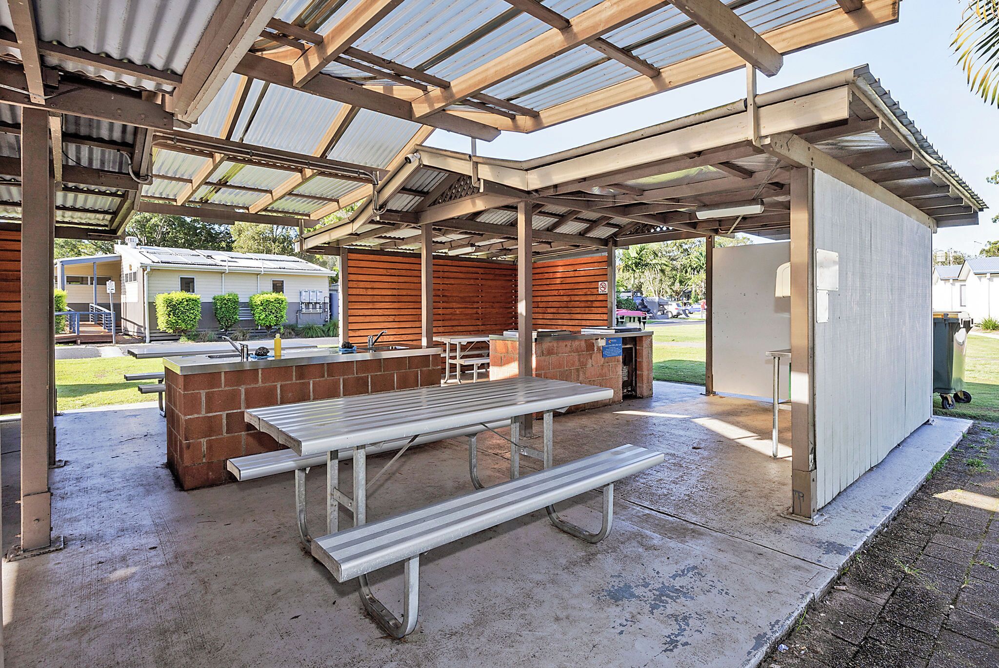Un patio exterior con una mesa de picnic, una parrilla y una zona de estar cubierta.