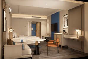 Habitació d'hotel amb llit, escriptori, cadira, sofà i televisió.